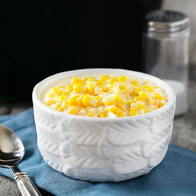 Bowl of Creamed Corn with crockpot in the background.