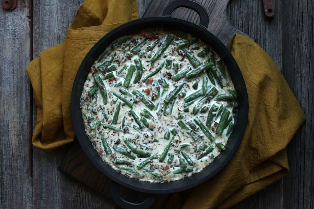 An overhead shot of a bubbling green bean casserole in a black baking dish.