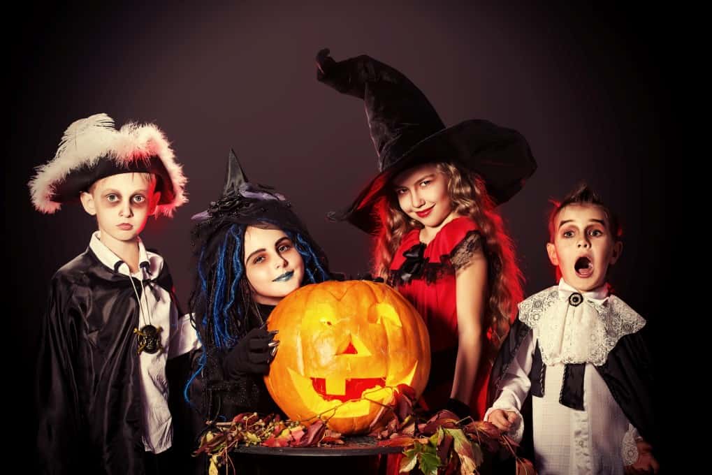 Children dressed up for Halloween with a carved out pumpkin