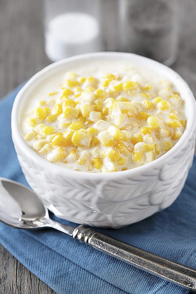 Bowl of creamy corn with salt and pepper shakers.