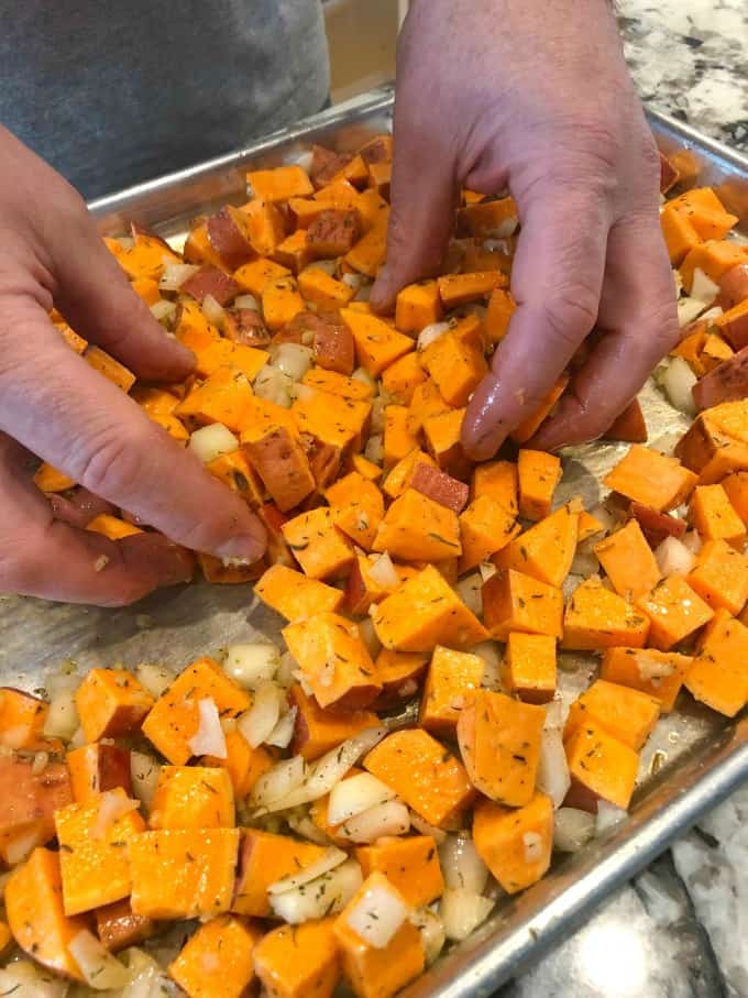 Tossing sweet potato onion mixture on a baking sheet