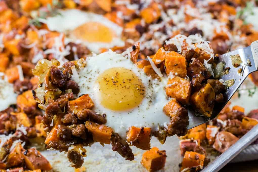 Sweet Potato Hash with Eggs and Sausage on a spatula taken from a sheet pan