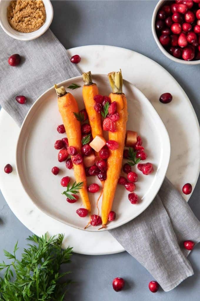 3 carrots on a plate with cranberries