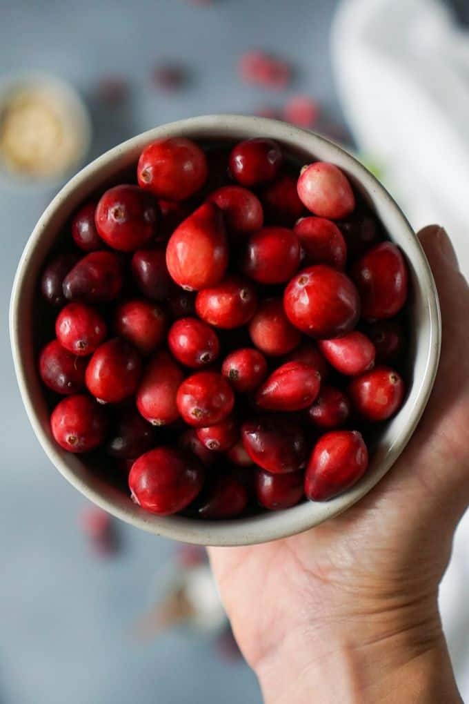 a hand holding a bowl of cranberries