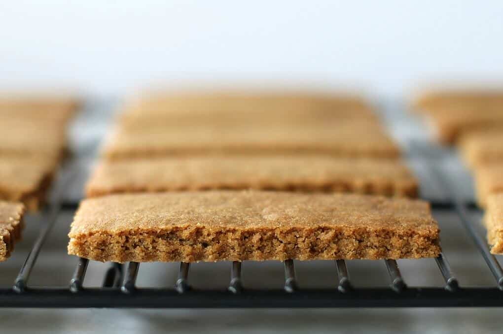 A black backing rack holds twelve brown rectangular cookies in a neat row.