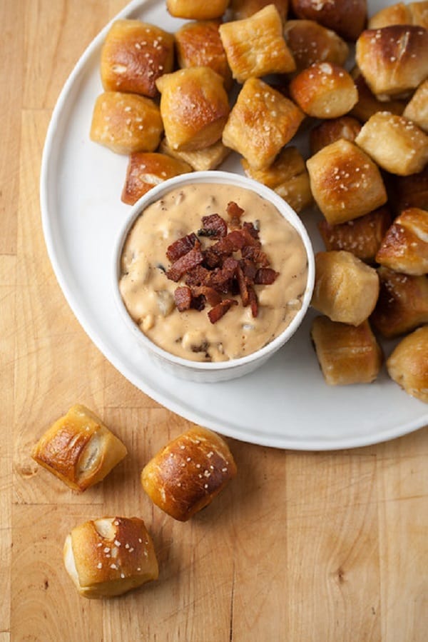 Bacon jalapeno cheese dip in a white bowl with pretzel bites on a white plate