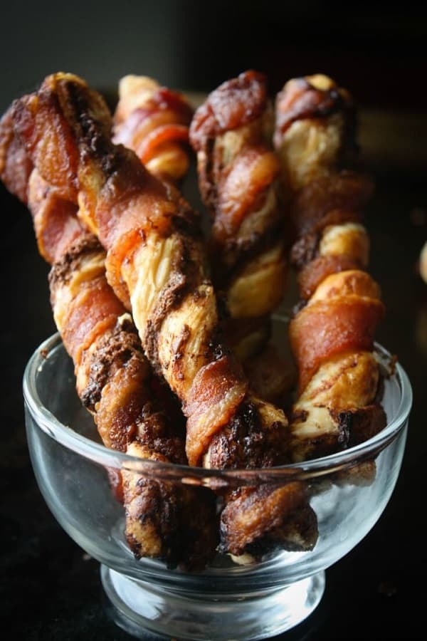 Chocolate bacon twists standing in a clear glass bowl