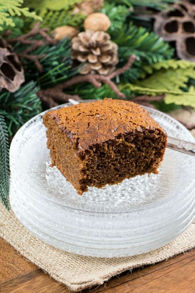 Gingerbread cake on clear glass stack of plates with greenery in the background