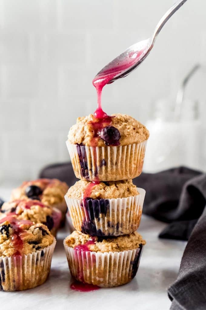a spoon drizzling lemon blueberry glaze on a muffin