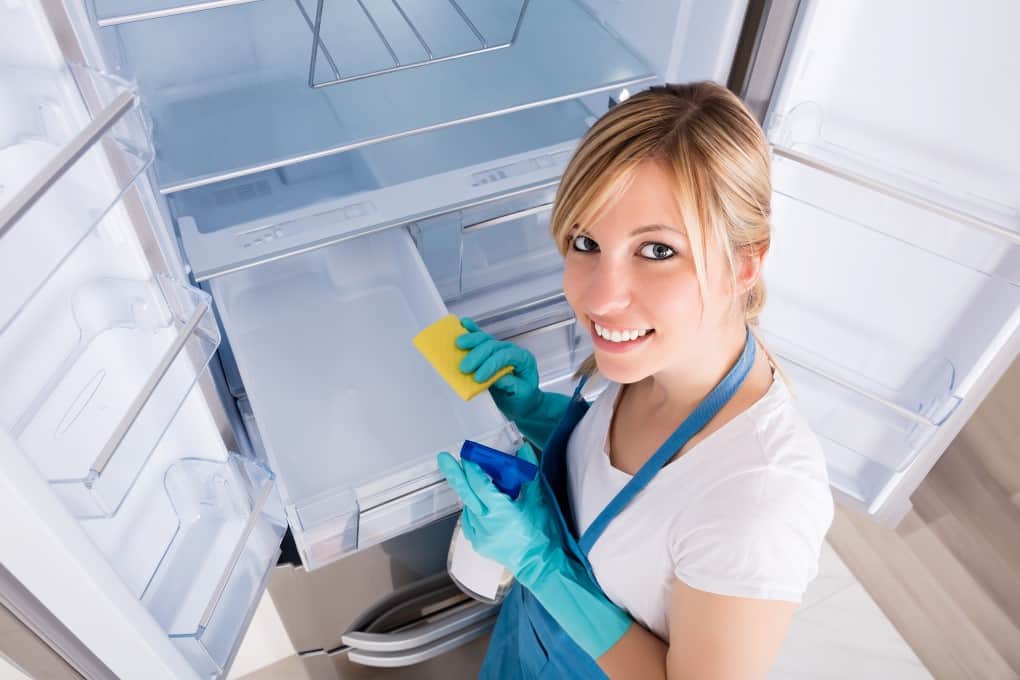 High Angle View Of Young Woman Cleaning Empty Refrigerator