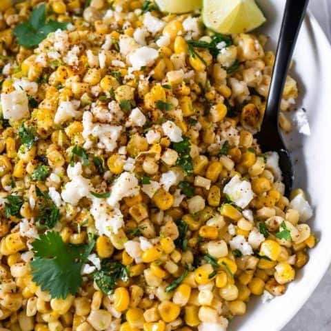 Mexican corn dip in a big white bowl with a black spoon
