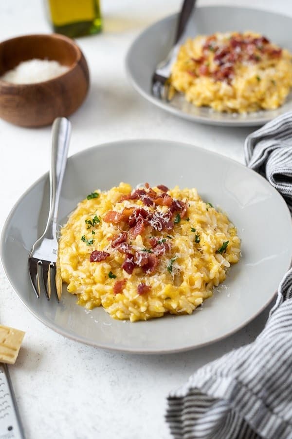 Pumpkin risotto with bacon in a white bowl with a fork