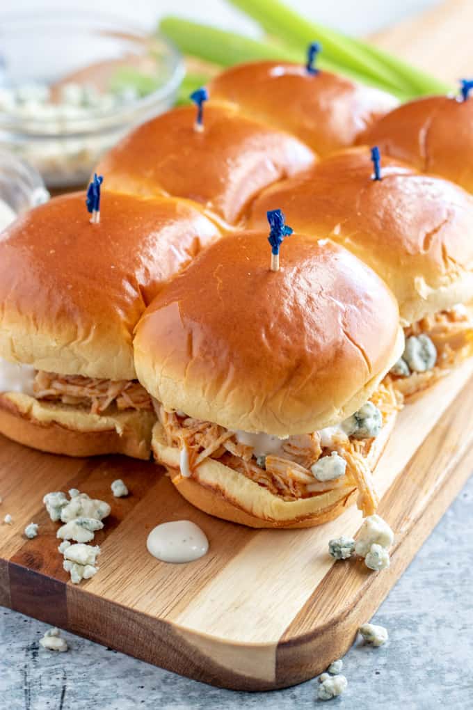 buffalo chicken sliders with blue cheese and ranch on a woodent board