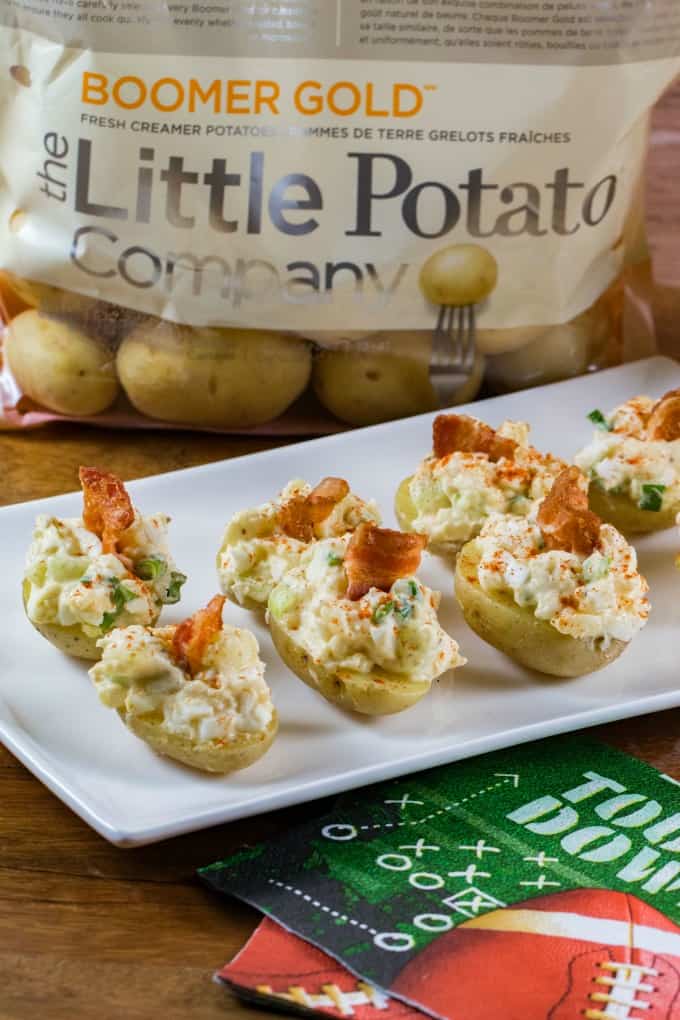 Creamer potatoes Stuffed with Egg Salad on a platter with a bag of Little potatoes in the background