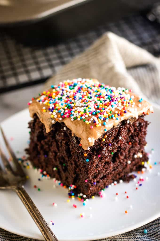 chocolate sheet cake with sprinkles - on a white plate with a fork