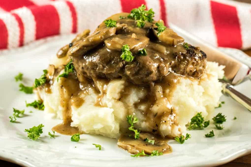 Horizontal of Salisbury Steak on mashed potatoes on a white plate