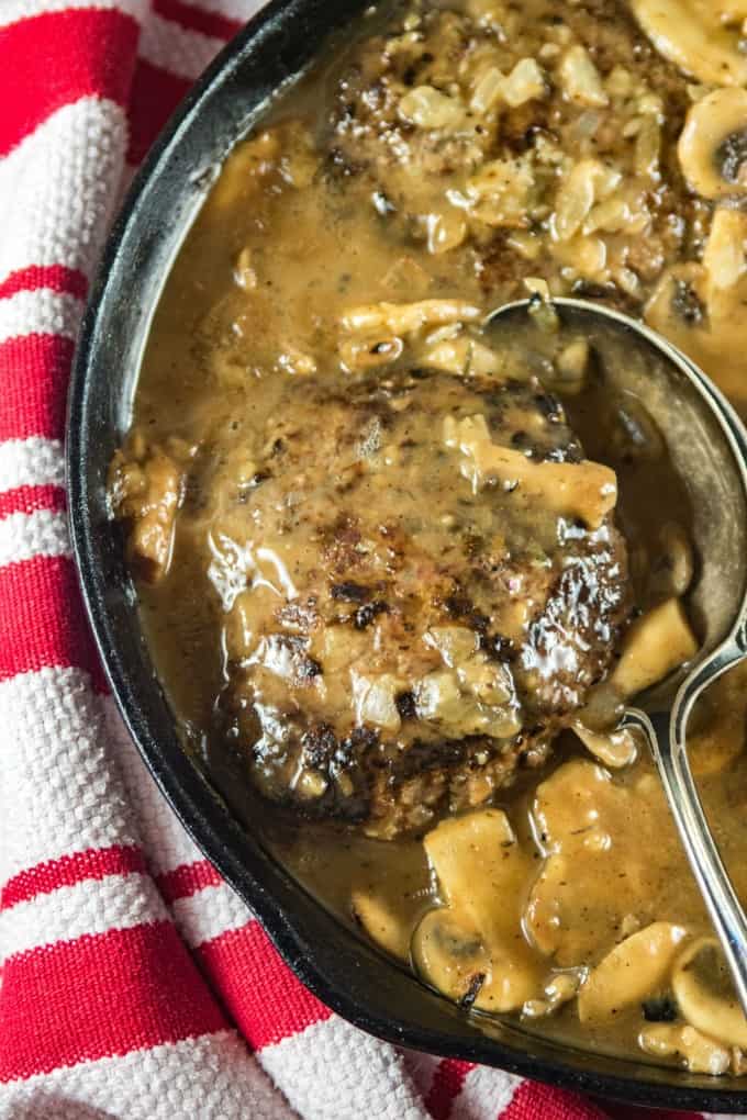 Salisbury Steak in a cast iron pan with a red and white tea towel