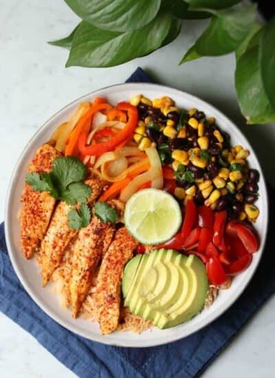 Healthy Chicken Burrito Bowl - overhead photo featuring a bowl filled with healthy vegetables, bean salad, avocado, rice, and chicken tenders.