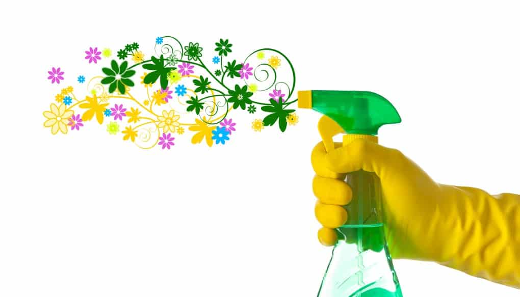 Spring cleaning concept. Floral detergent sprayed by a hand with yellow glove.