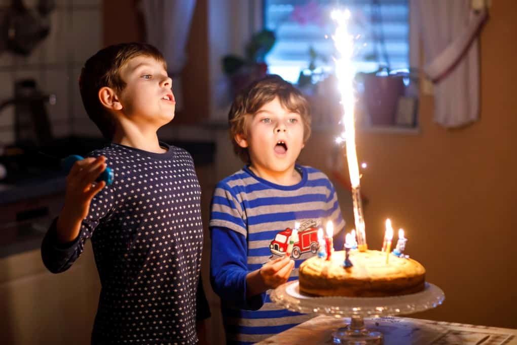 Two beautiful kids, little preschool boys celebrating birthday and blowing candles 