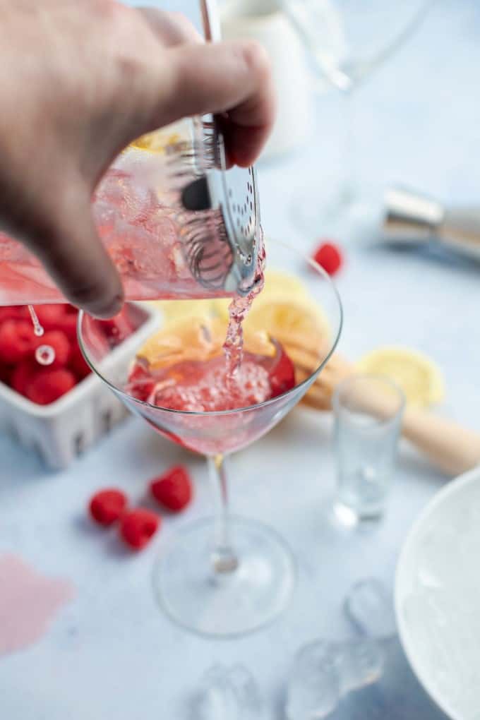 Pouring a Bramble cocktail into a martini glass