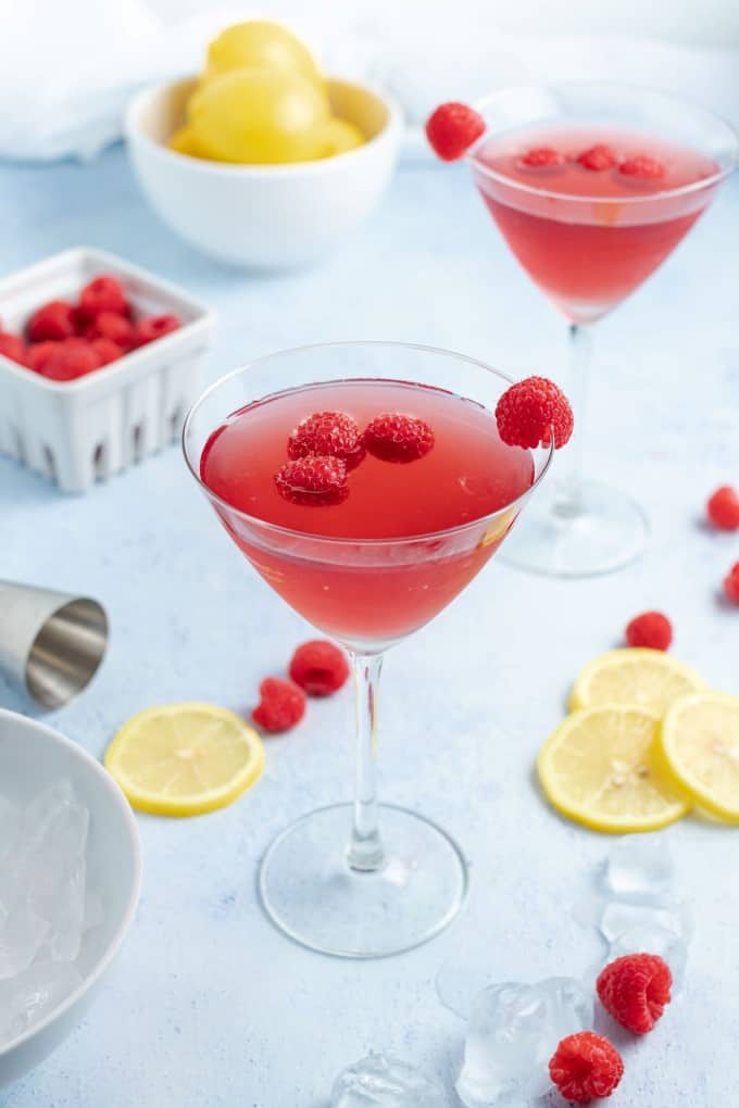 Chambord Bramble Cocktail with raspberries and sliced lemons on white