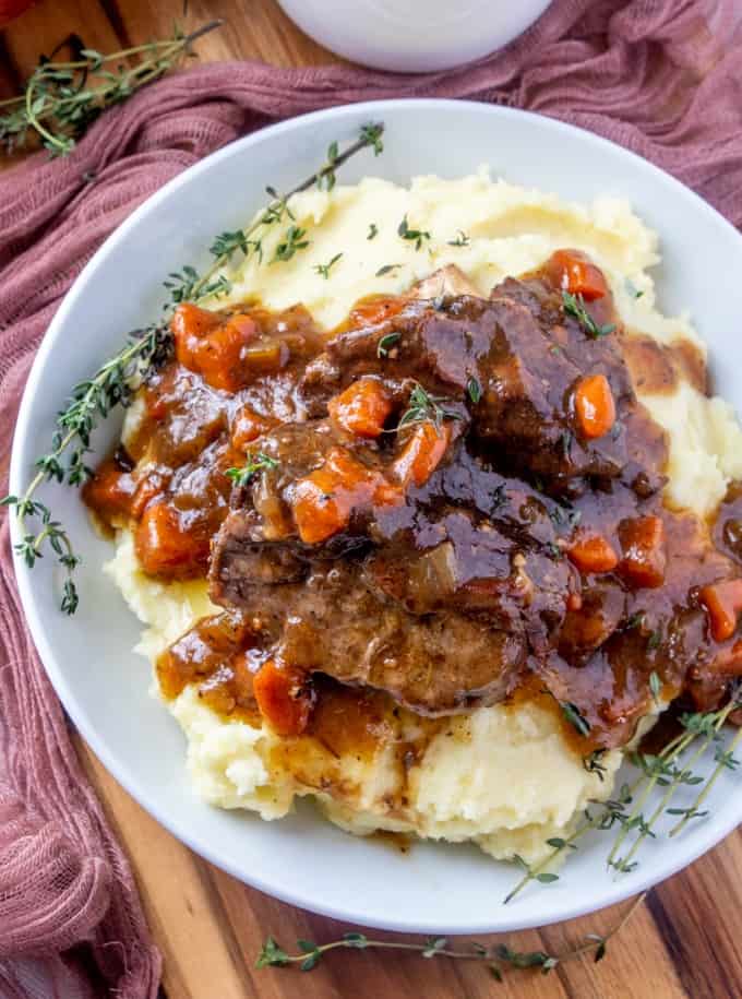 Overhead view of beef ribs in sauce on mashed potatoes