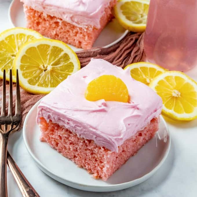 Pink Lemonade Cake on a plate with forks and lemon slices