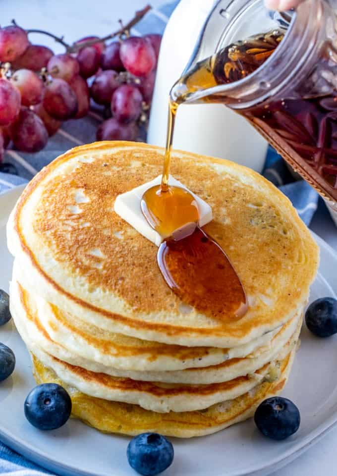 Pouring maple syrup on pancakes