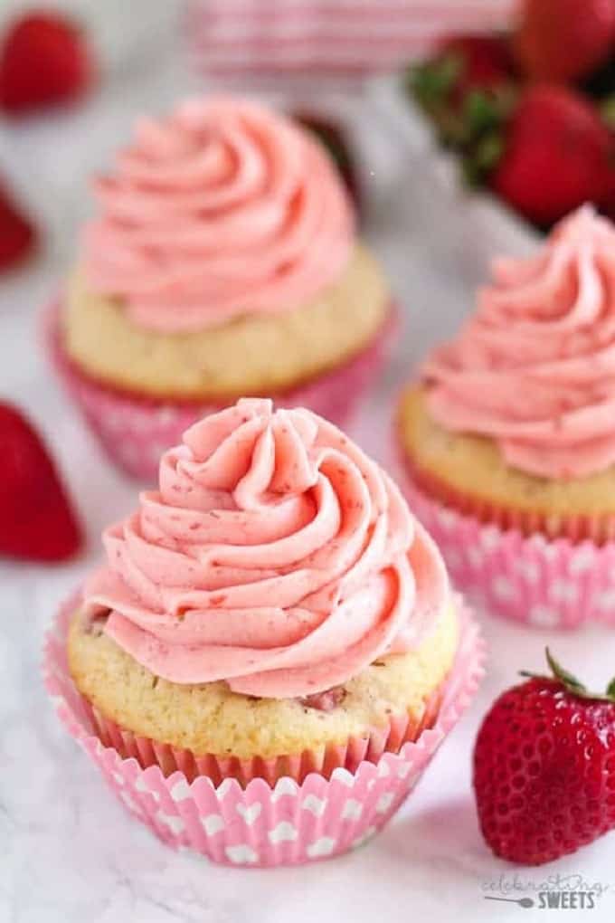 Fresh strawberry cupcakes on a white table with fresh strawberries around them