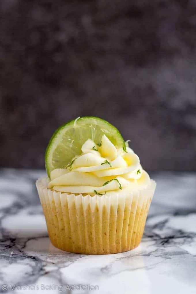 Margarita cupcake with a lime slice in the frosting on a marble table