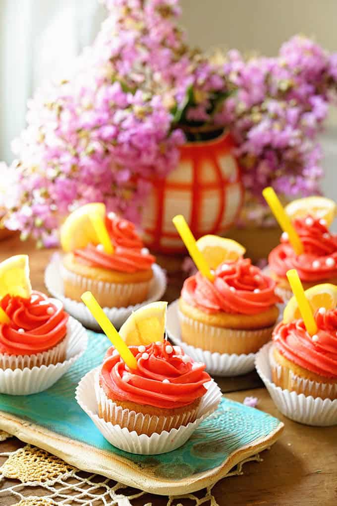 Pink Lemonade cupcakes on a table with flowers in the background