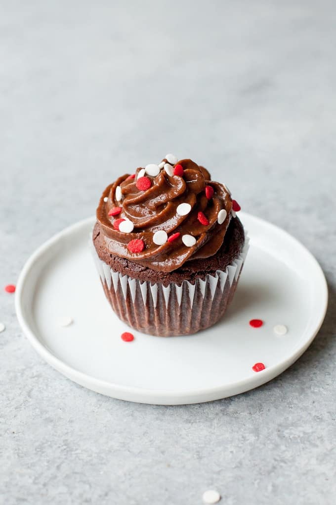 Small batch healthier chocolate cupcake with red and white sprinkles on a white plate