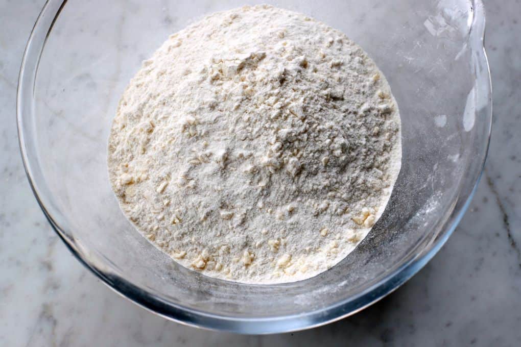 A glass bowl containing flour texture when properly crumbled with butter.