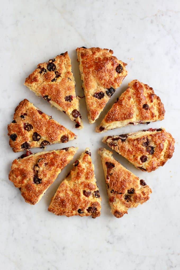 A circle of golden baked blueberry scones on a white marble counter.