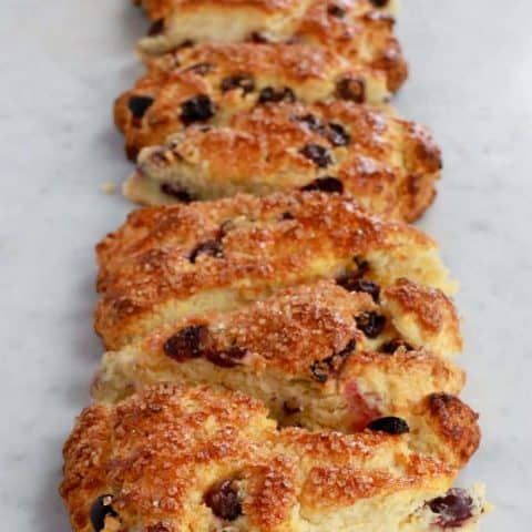 Buttermilk Blueberry Scones - A vertical row of golden baked blueberry scones on a white marble counter.