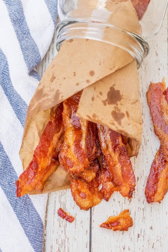 Brown Sugar Bacon wrapped in brown paper and stuffed in a jar lying on its side. 