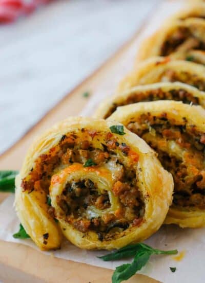 Close up of a sausage pinwheel row on a wooden board.