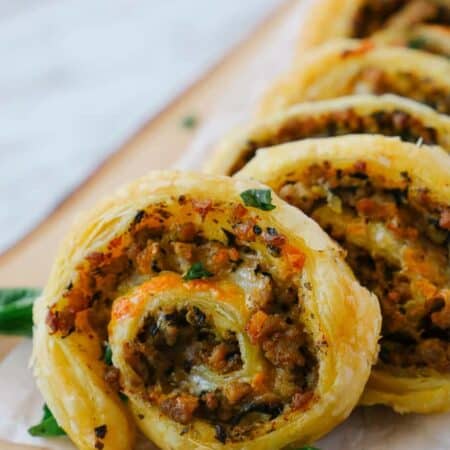 Close up of a sausage pinwheel row on a wooden board.