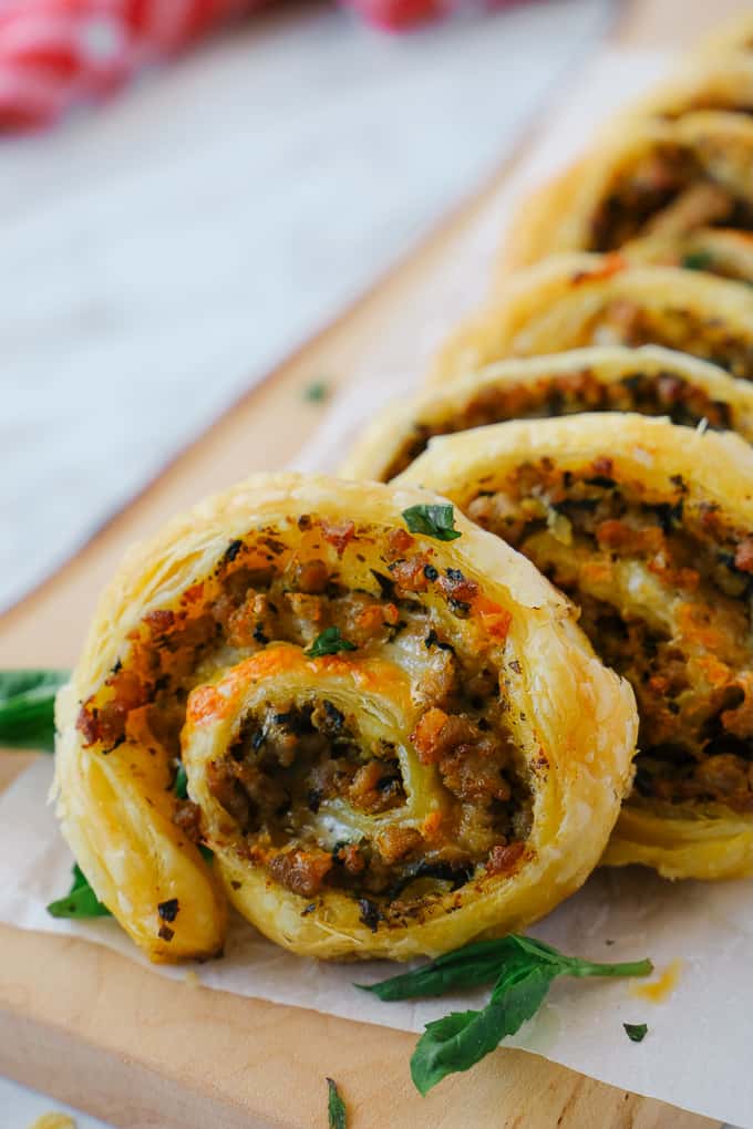 Close up of a sausage pinwheel row on a wooden board.