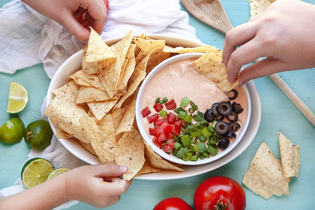 Hands Scooping Mexicali Dip with chips