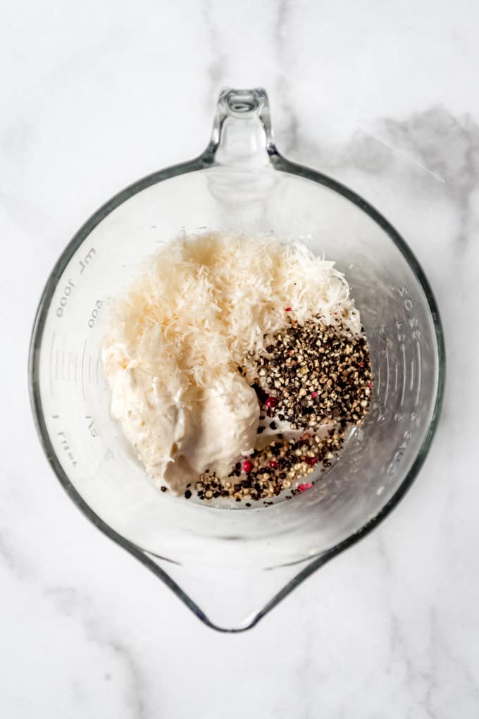 Parmesan peppercorn dressing - A glass bowl with the ingredients for parmesan peppercorn dressing.