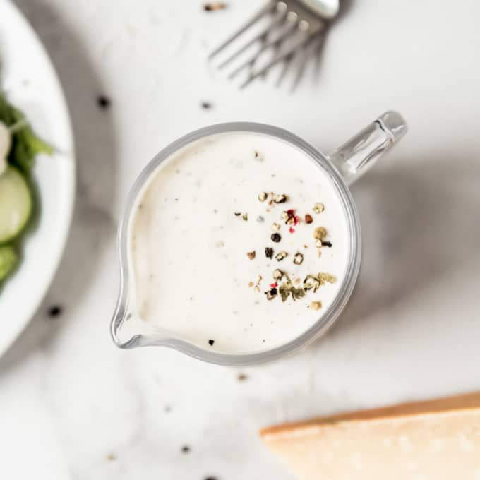 Parmesan peppercorn dressing - An overhead shot of a glass pitcher with creamy parmesan peppercorn dressing.