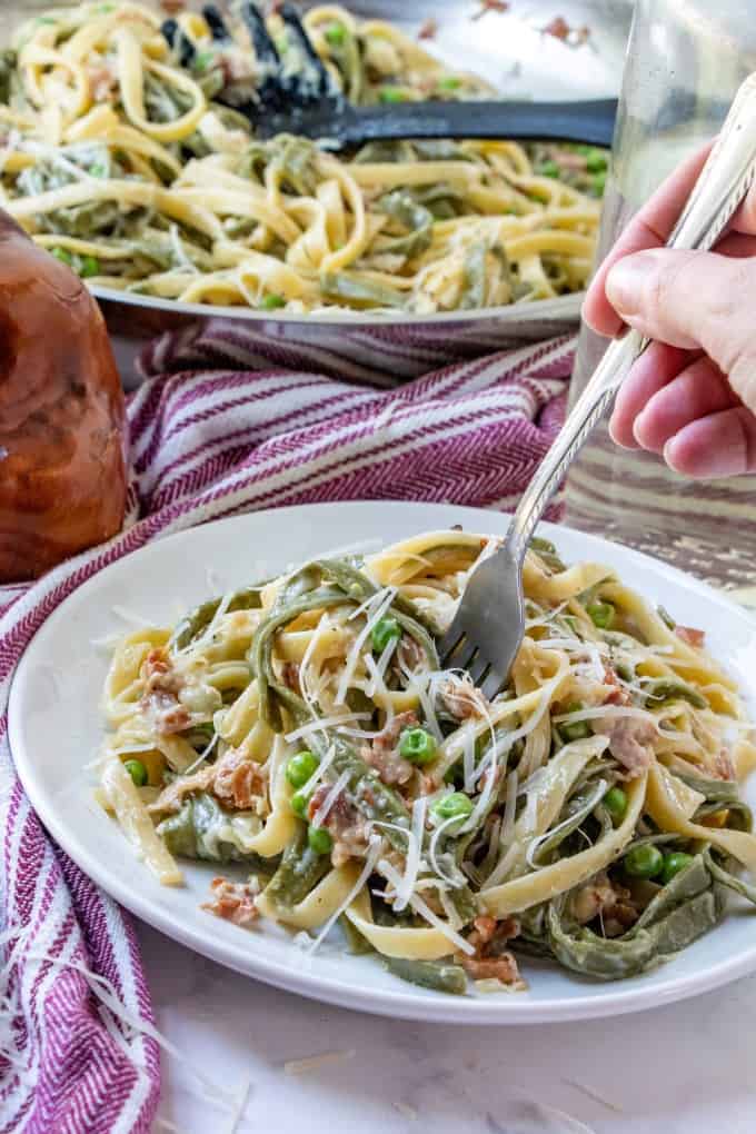 A fork diving into Paglia e Fieno on a white plate