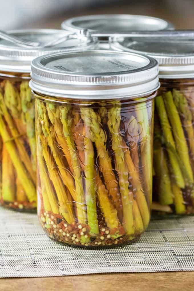 Fork resting on tops of asparagus in jars