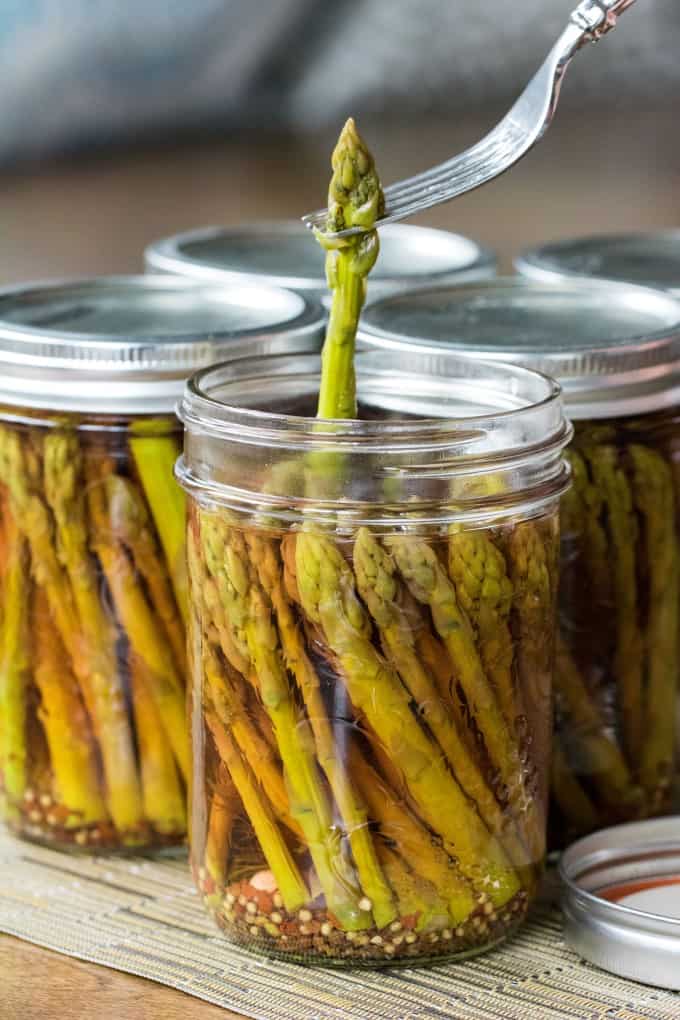 Pulling an asparagus spear out of a jar with a fork