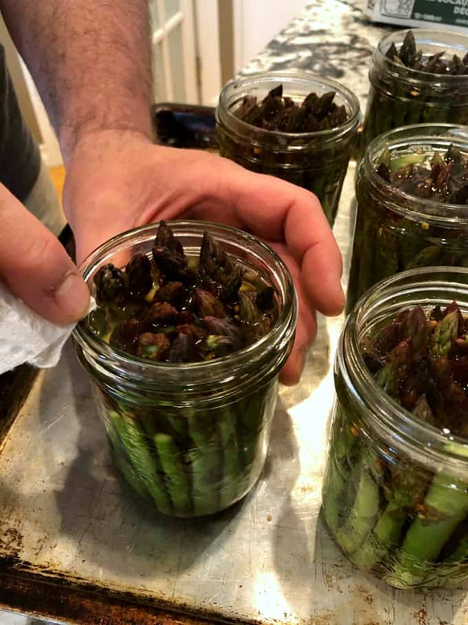Wiping down the rims of jars of asparagus