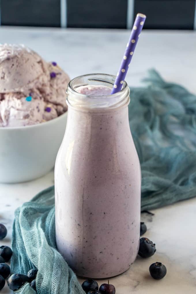 Blueberry milkshake with a bowl of ube ice cream in the background