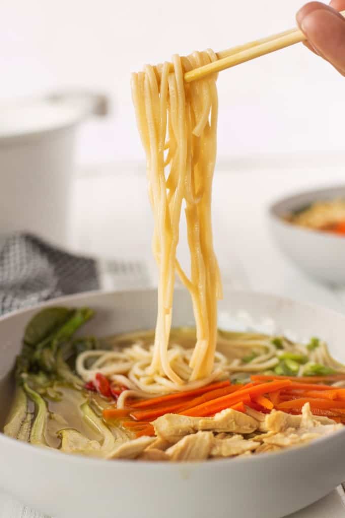 Pulling noodles from a bowl of soup with chopsticks