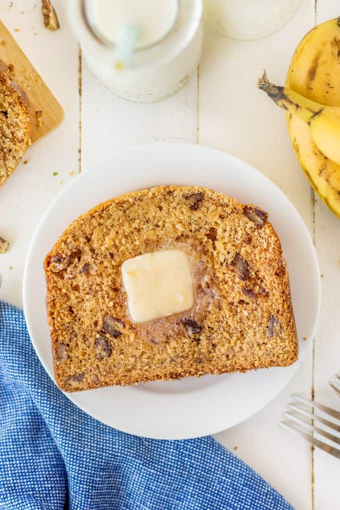 Banana bread on a white plate with a pat of butter